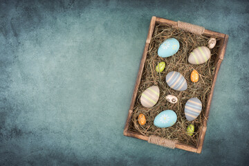 Colored easter eggs in a basket with hay, empty copy space for text
