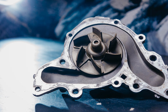 Used Water Pump For Car Engine Cooling System On Blue Background.