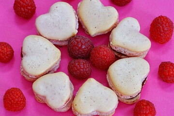 Pink heart shaped macaron cookies with fresh raspberries