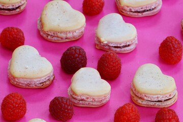 Pink heart shaped macaron cookies with fresh raspberries