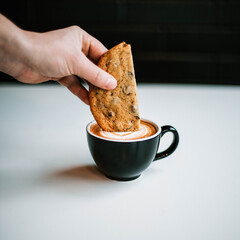 hand dipping cookie into coffee