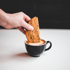 person holding a cookie oin coffee
