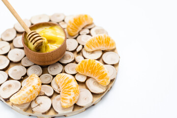 honey in a wooden bowl and orange on a white background.