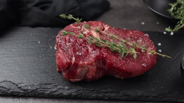 fresh raw beef steak meat slice on black stone plate. meat and spices on kitchen table