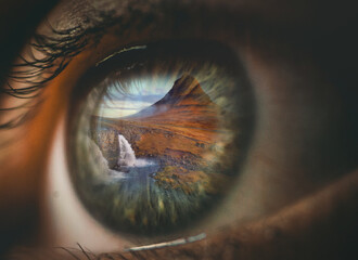 double exposure of an eye reflecting a mountain landscape