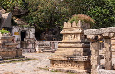 Anegundi, Karnataka, India - November 9, 2013: Navabrindavana island and temple. Closeup of ruinous brown stone building with green foliage screen in back.