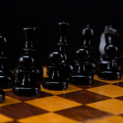 Black chess pieces on a chessboard. An army of black pawns on the table