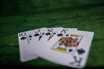 Closeup view of some Poker playing Cards over a green Texture wooden table
