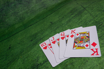 Closeup view of some Poker playing Cards over a green Texture wooden table
