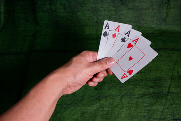 Male hand holding Poker playing Cards over a green Texture wooden table
