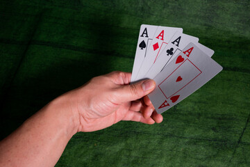 Male hand holding Poker playing Cards over a green Texture wooden table
