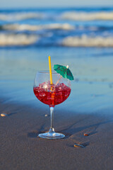 A delicious and refreshing cocktail on the sand of the beach near the waves.