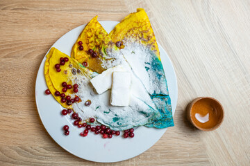 colored pancakes with berries, butter and honey