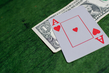 Male hand of compulsive gambler holding Poker Cards over a green Texture wooden table, gambling with some american dollars 