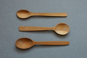 three brown empty wooden spoons lies on a gray table