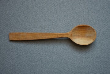 one brown empty wooden spoon lies on a gray table