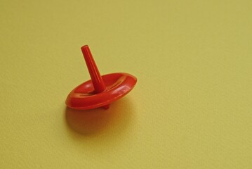 one small red plastic toy whirligig stands on a yellow table