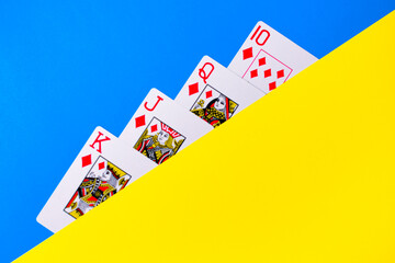 Closeup view of some Poker playing Cards over a blue and yellow table
