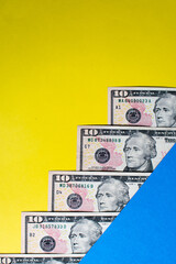 Closeup view of some dollar bills over a blue and yellow table
