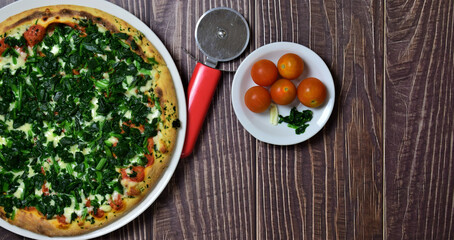 Spinach pizza on rustic wooden table. Copy space.