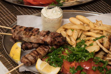 .Fried souvlaki with greek salad, potatoes and tzatziki sauce in plate