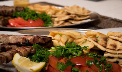 .Fried souvlaki, traditional lamp kebab with fresh salad and sauce in plate on wicker surface.