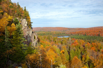 Cliff and small lake surrounded by trees in fall color in northern Minnesota
