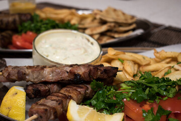 .Fried souvlaki with greek salad, potatoes and tzatziki sauce in plate