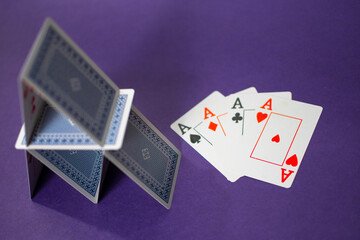 House of cards with some poker cards over a purple background
