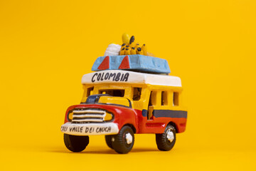Colorful souvenir toy car vehicle with the colors of Colombia. Studio still life toy against a seamless yellow background