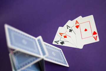 House of cards with some poker cards over a purple background
