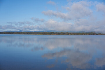 Fototapeta premium Lake dam landscape with reflection of Gardunha mountains and trees on a cloudy day in Santa Agueda Marateca Dam in Portugal