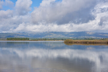 Lake dam landscape with reflection of Gardunha mountains and trees on a cloudy day in Santa Agueda Marateca Dam in Portugal