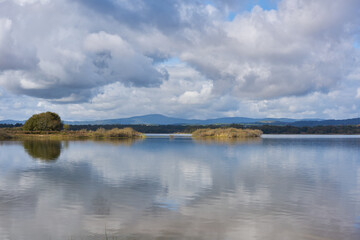 Lake dam landscape with reflection of Gardunha mountains and trees on a cloudy day in Santa Agueda Marateca Dam in Portugal