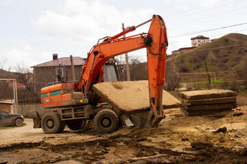 Obraz premium An excavator lifts concrete slabs during excavation work.