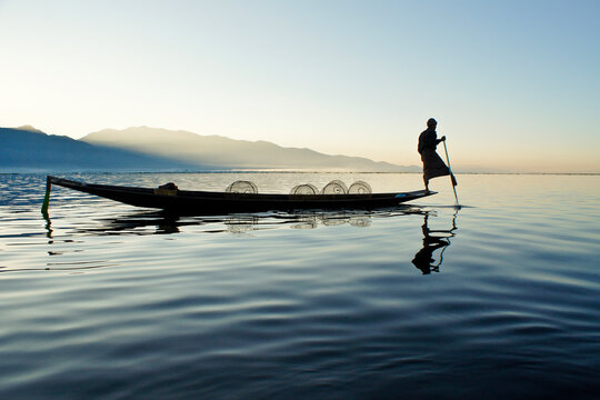 Intha leg-rowing fisherman with fish traps on Inle Lake at sunrise, Myanmar (Burma)