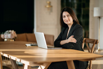 Economist accountant a woman in a business suit types a message to colleagues. Modern and stylish office. A professional Manager is sitting in a chair working on a laptop computer.