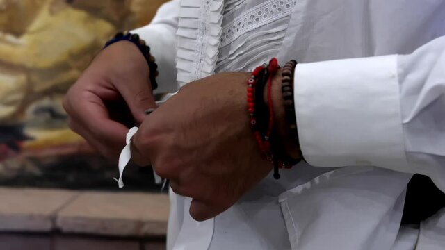 Male bullfighter hands calmly tying his white shirt