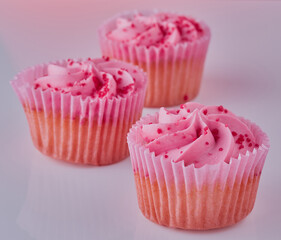 Pink cup cakes on a white surface.