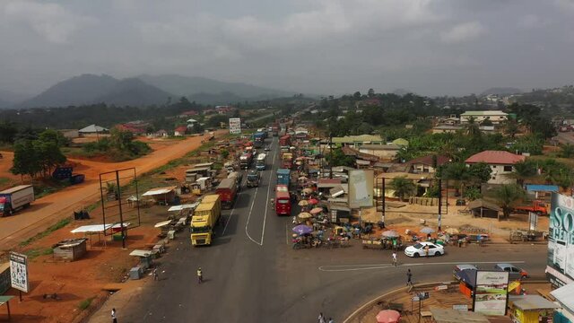 Aerial Ghana Africa highway trucks and vendors fast motion. Old busy congested market area and truck parking in rural village between Accra and Kumasi Ghana, Africa. Place to buy and sell products.