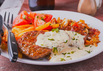 Steak burgers with fries and sauce.
