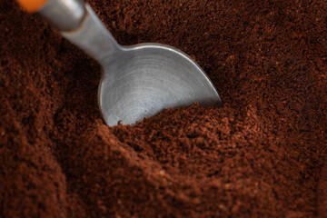 Exetreme close-up of ground coffee powder with an iron spoon inside of it. Copy space.