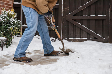 Closeup of man shoveling  show from a sidewalk with a standard shovel