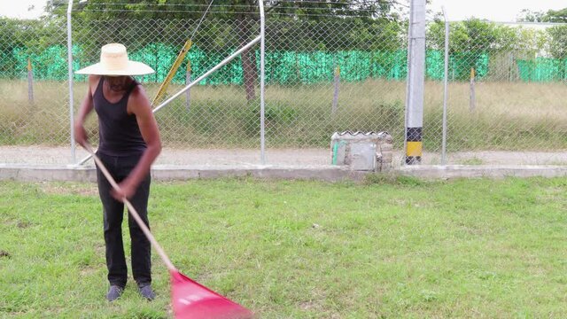 Hombre afroamericano  recoge la basura en su jard&iacute;n  bajo un fuerte sol