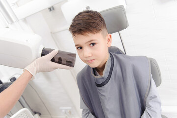 Obraz premium Dentist hands make jaw x-ray image for little boy in dental clinic