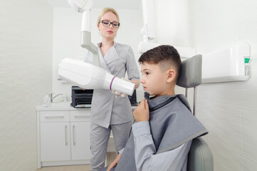 Dentist hands make jaw x-ray image for little boy in dental clinic