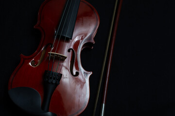 Fototapeta premium Close view of a classical small violin, strings and bridge over a dark black blanket background 