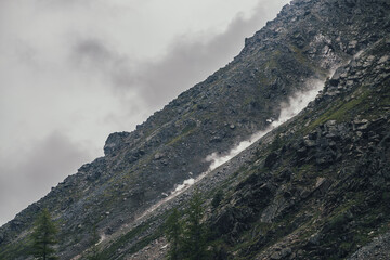 Good shot of rockfall on rocky mountain steep slope and long trail of dust. Good moment of...