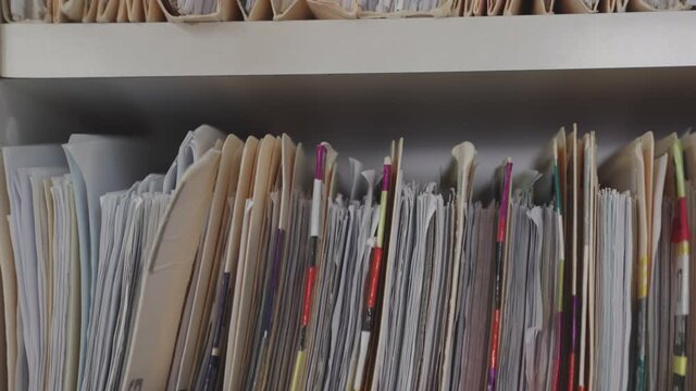 Medical cards on shelves in hospital. Health insurance folders in archive files. Records and catalogs in medicine clinic. Patient healthcare information