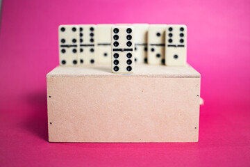 Old fashioned dirty domino on a box with pink solid backround
